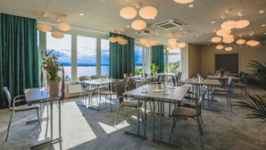 A conference room with tables and chairs, large windows with curtains, and hanging paper lanterns. - Almåsa Havshotell (Vasterhaninge)