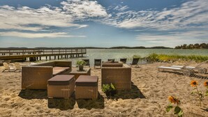 A beachside lounge with wicker furniture and a view of the water. - Almåsa Havshotell (Vasterhaninge)