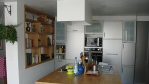 Cocina compacta con isla central, armarios blancos y microondas.