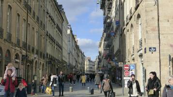 Una concurrida calle urbana con peatones, edificios históricos y letreros comerciales.
