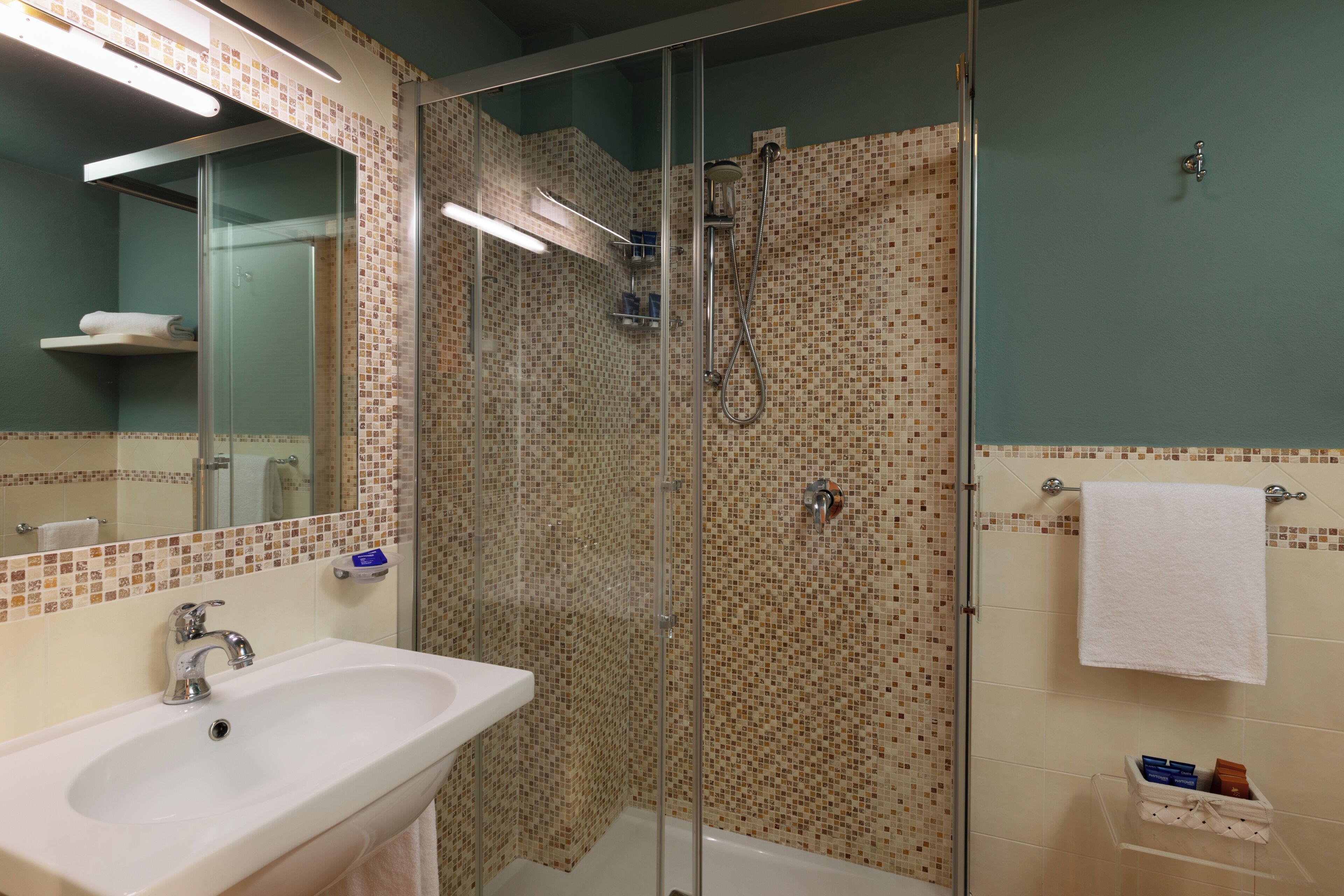 Un baño con ducha de vidrio, lavamanos y espejo.