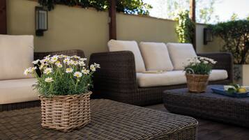 Muebles de mimbre, una cesta de mimbre con flores y un reposapiés de mimbre.