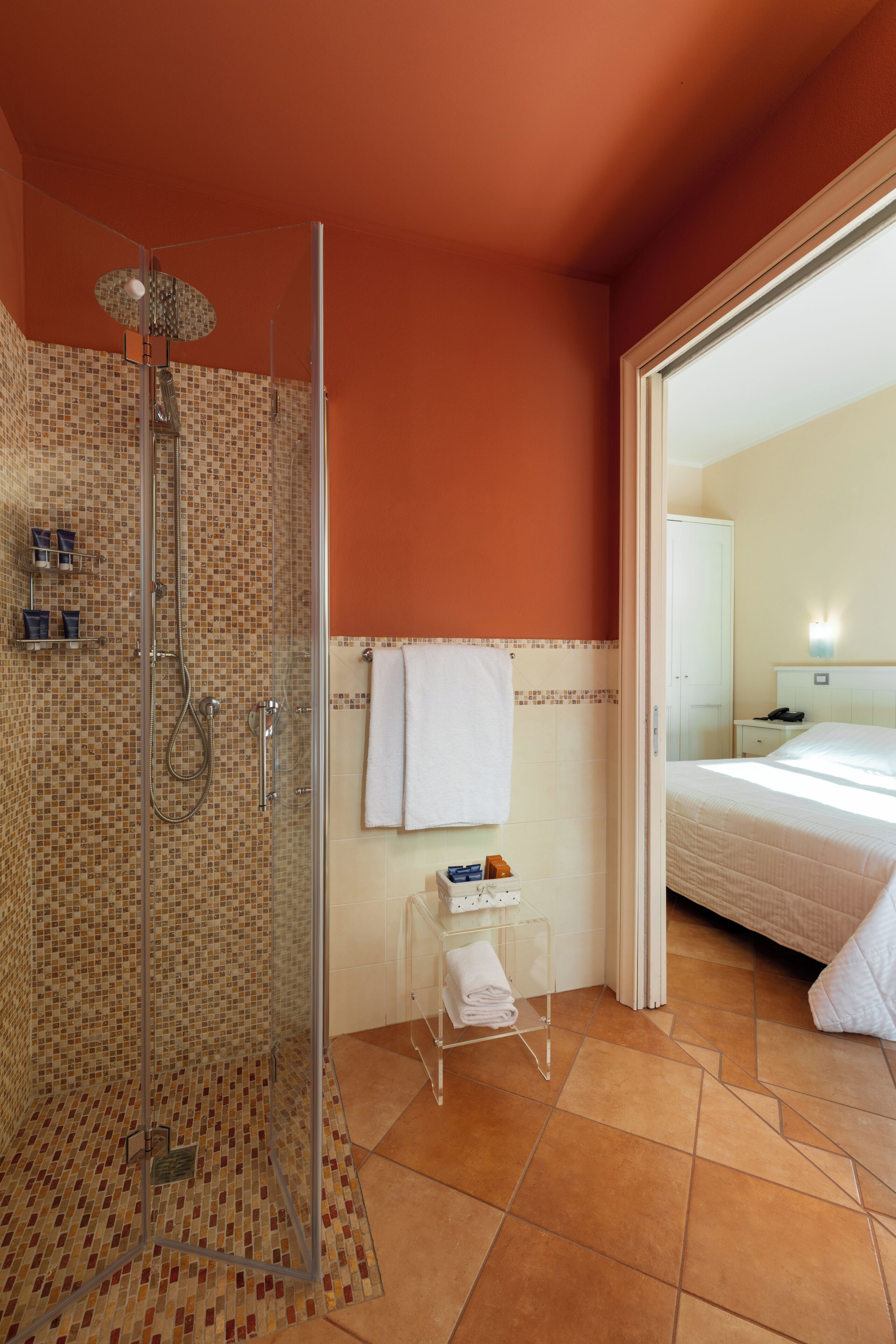 Une salle de bain d’hôtel équipée d’une douche, d’un porte-serviettes et d’une petite table sur laquelle sont posés les articles de toilette.