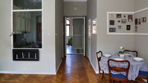 A dining area with a table set for four, a kitchen with cabinets, and a hallway leading to another room. - Boutique Apartments - Kazimierz (Kraków)