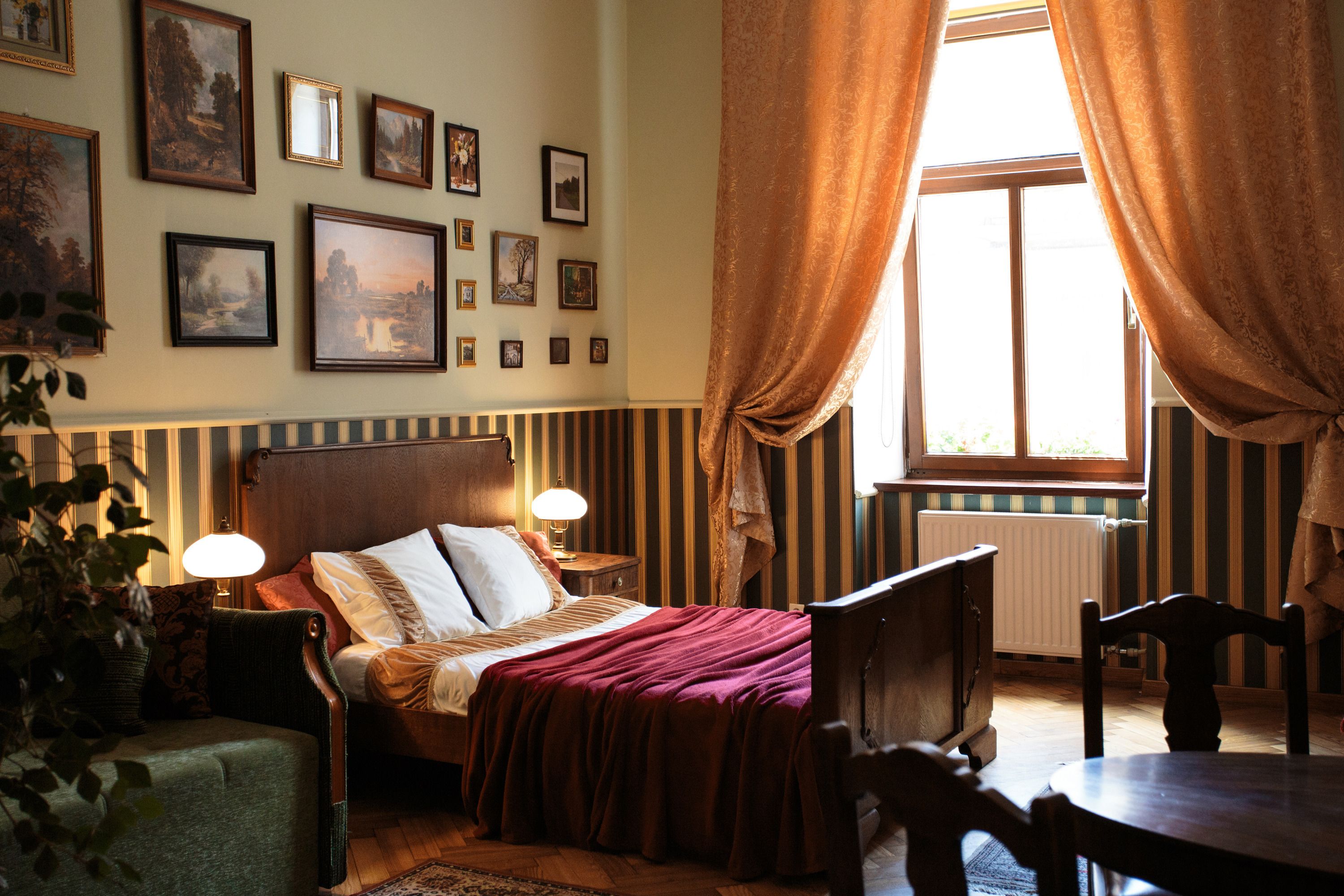 Una camera da letto con un letto, comodini, una sedia, un tavolo e una finestra con tende.