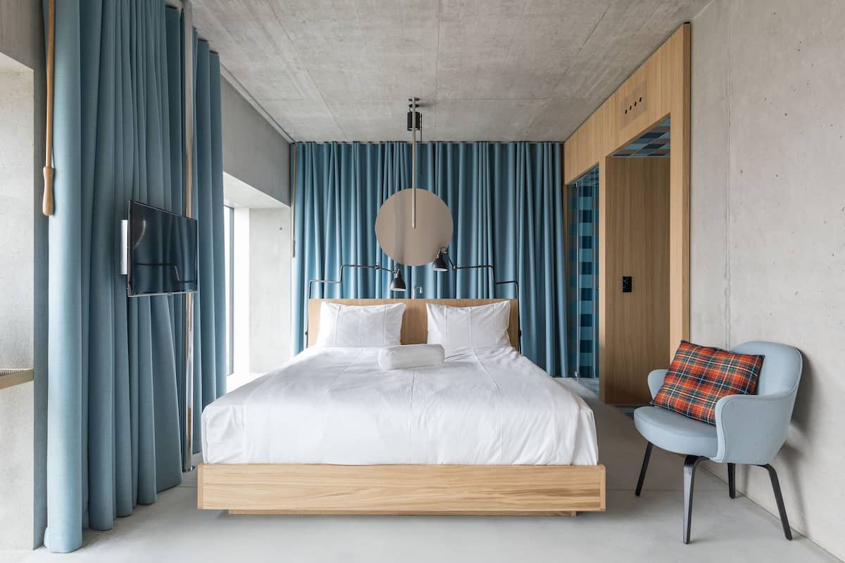 Une chambre moderne avec un grand lit, une chaise et des rideaux bleus.