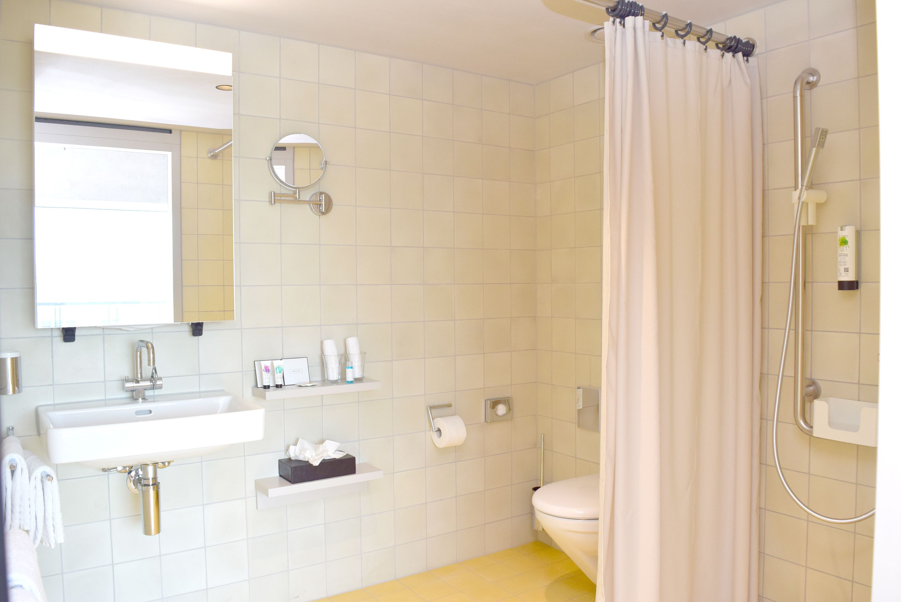 A bathroom with a sink, mirror, toilet, and shower.