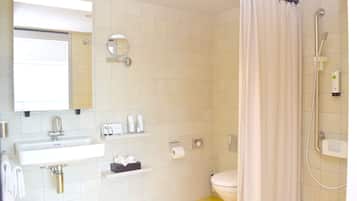 A bathroom with a sink, mirror, toilet, and shower.