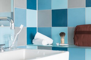 Een badkamer met een wit wastafel, een glas water, een tandenborstel, een opgerolde handdoek en een bruine tas.