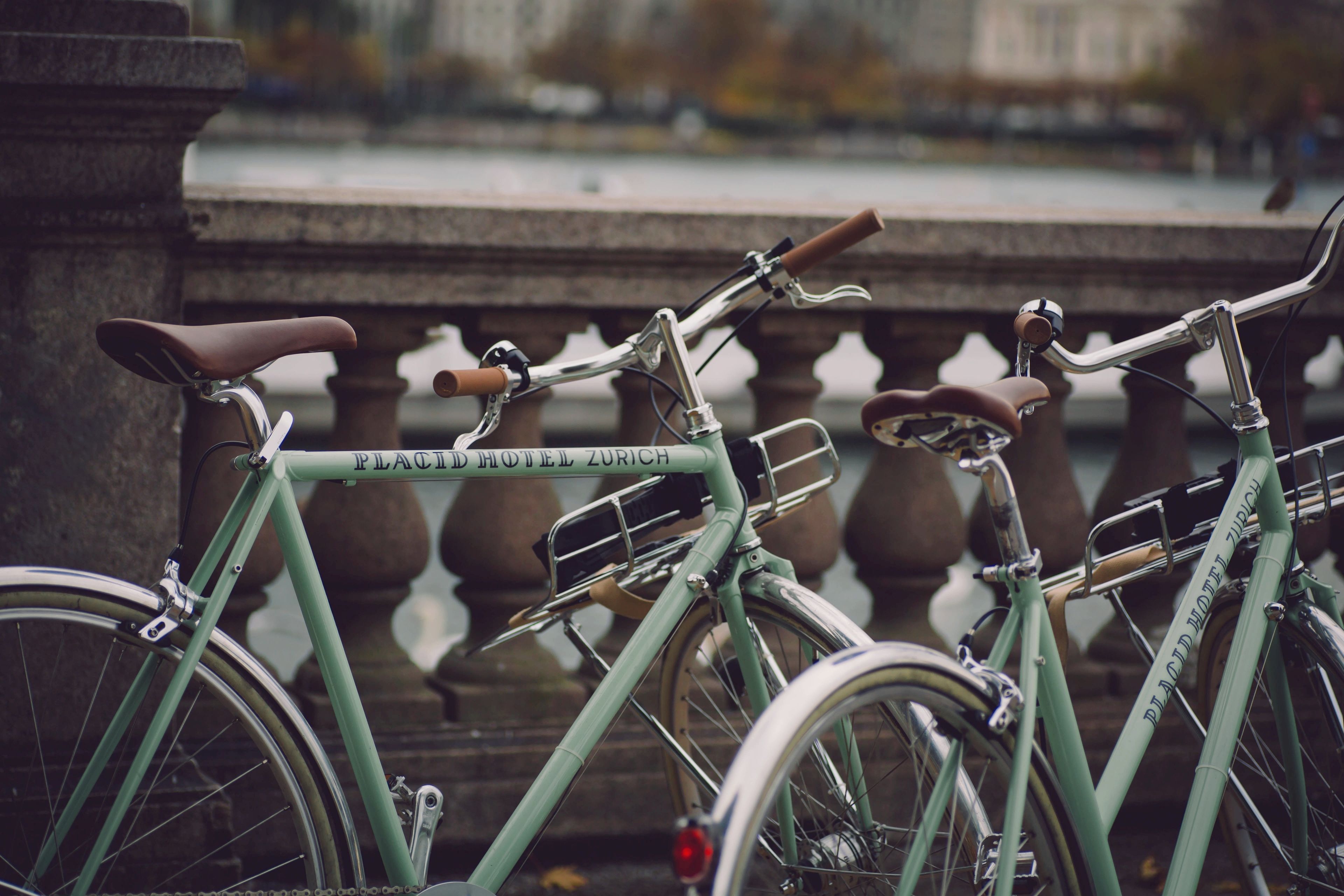 Un vélo sur lequel on peut lire les mots « Placid Hotel Zurich », garé près d’une balustrade en pierre, au bord d’un plan d’eau.