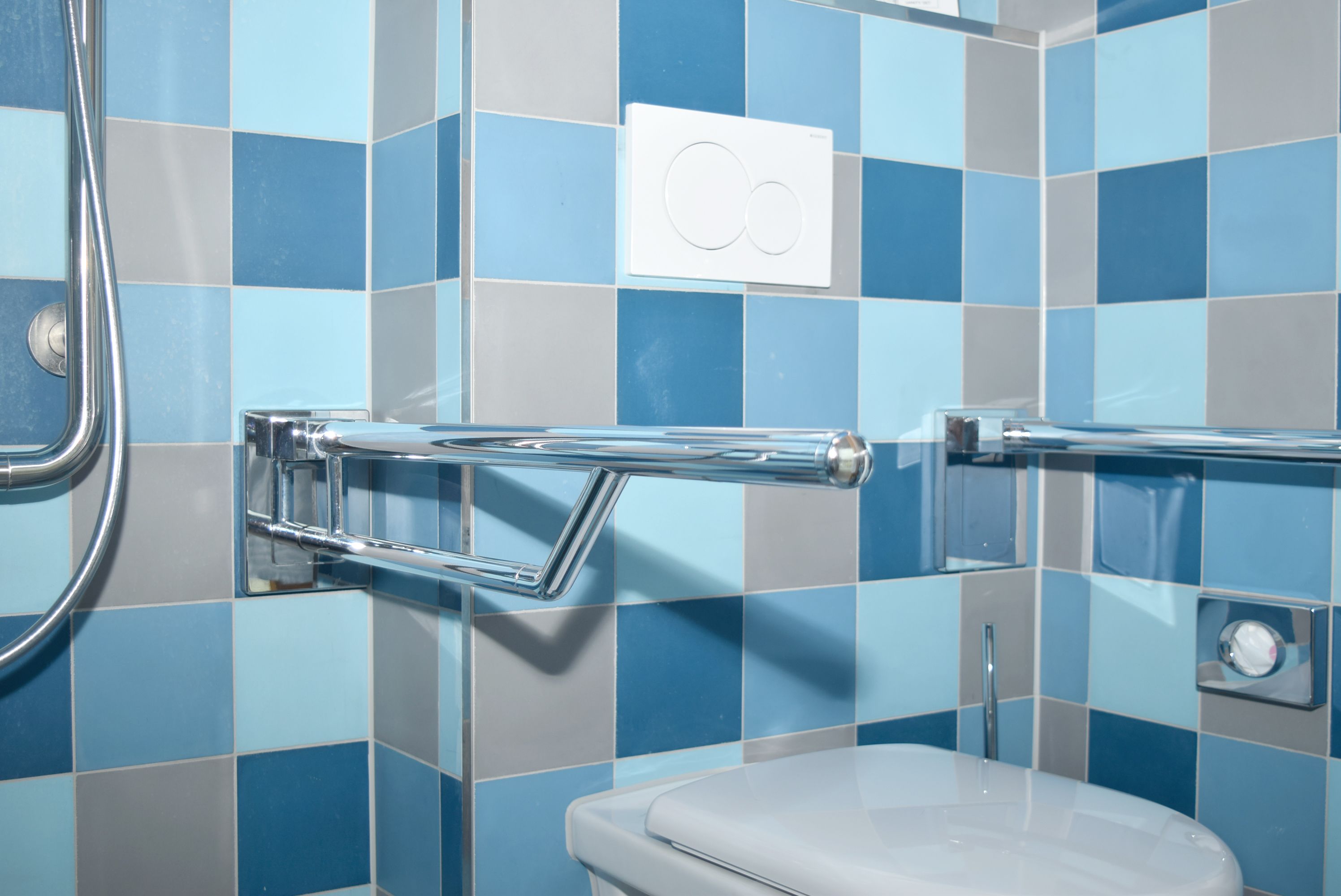 Ein Badezimmer mit blauen und grauen Fliesen, einer weißen Toilette und einem chromfarbenen Handtuchhalter.