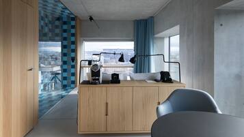 A modern kitchen with a wooden cabinet, a black countertop, and a view of the city through large windows.