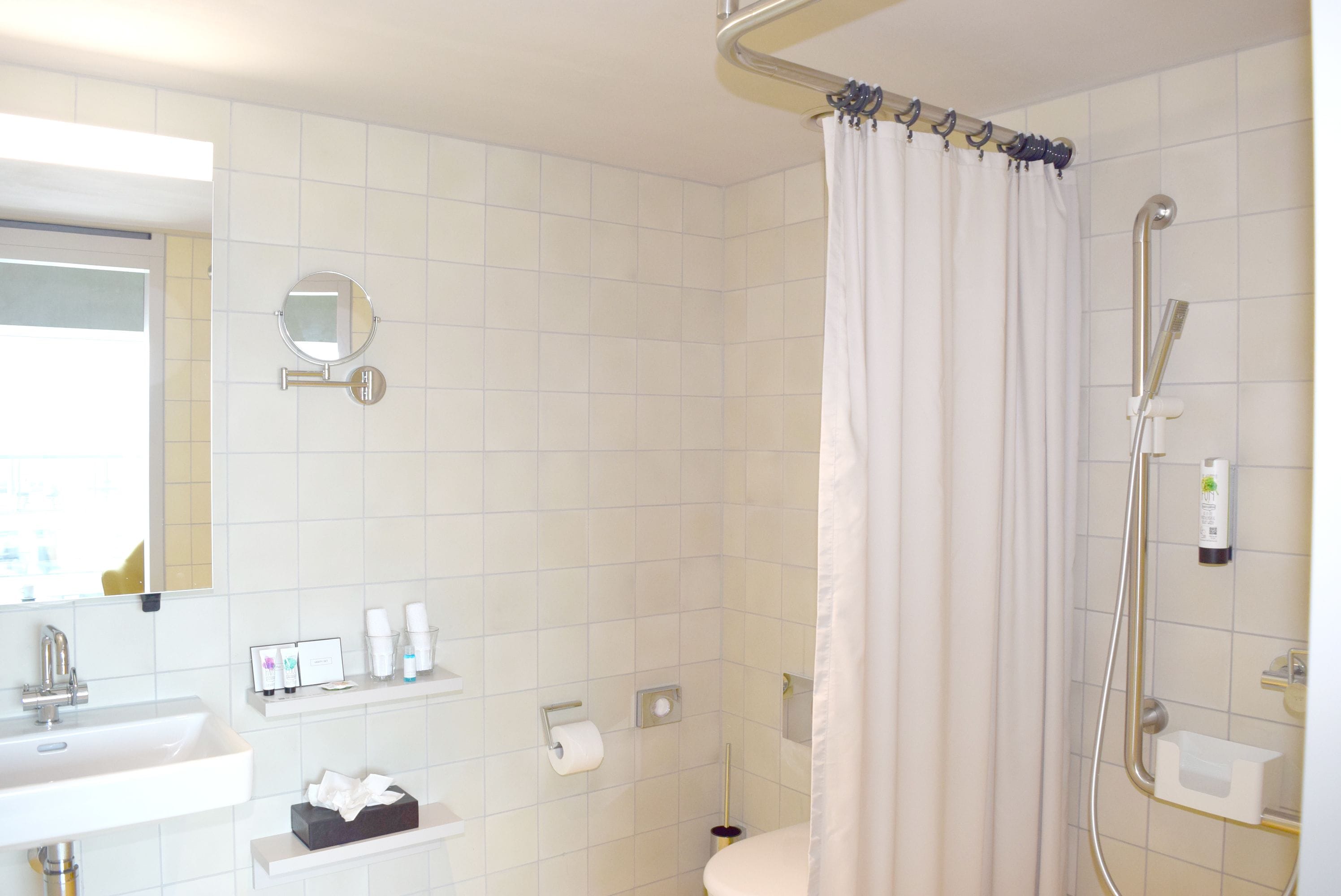 Un baño con ducha, inodoro, lavamanos y espejo.