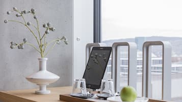 A modern interior with a white vase, a tablet, two glasses, and a green apple on a wooden table.