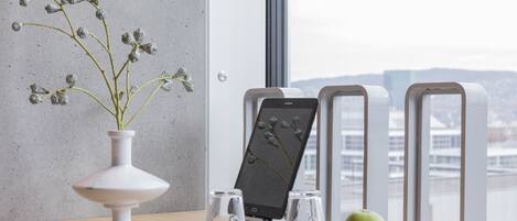 A modern interior with a white vase, a tablet, two glasses, and a green apple on a wooden table.