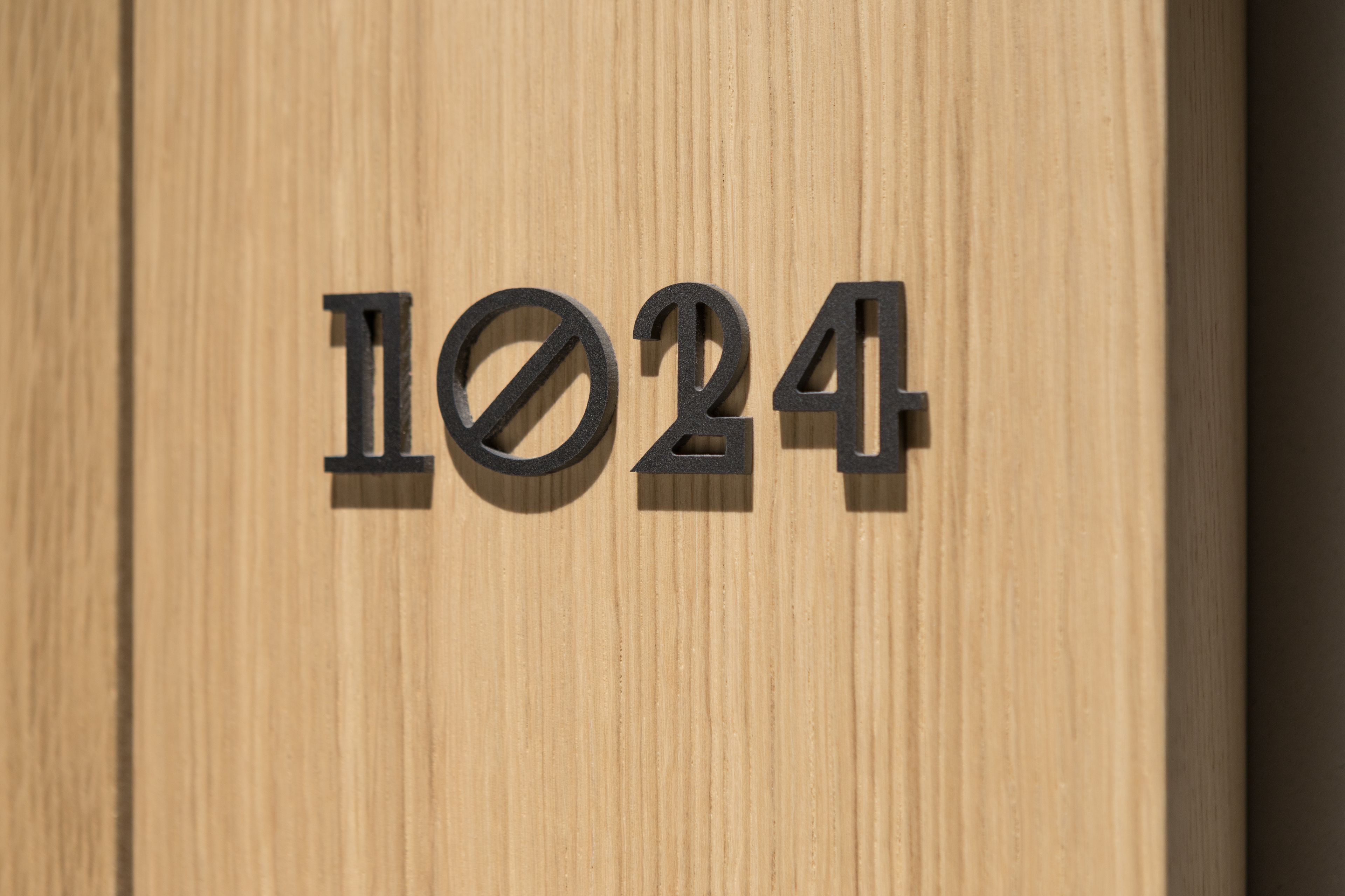 A wooden door with a black metal number plaque reading "1024".