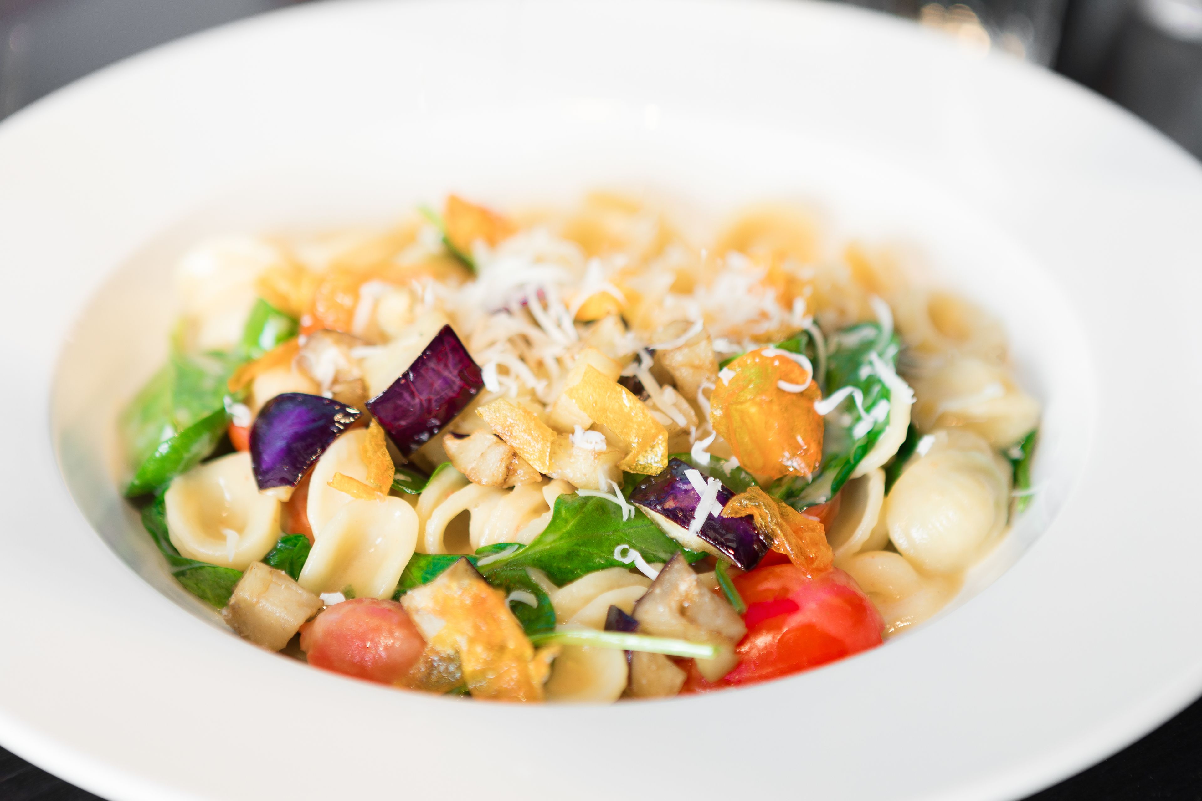 A plate of pasta salad with various vegetables and cheese.