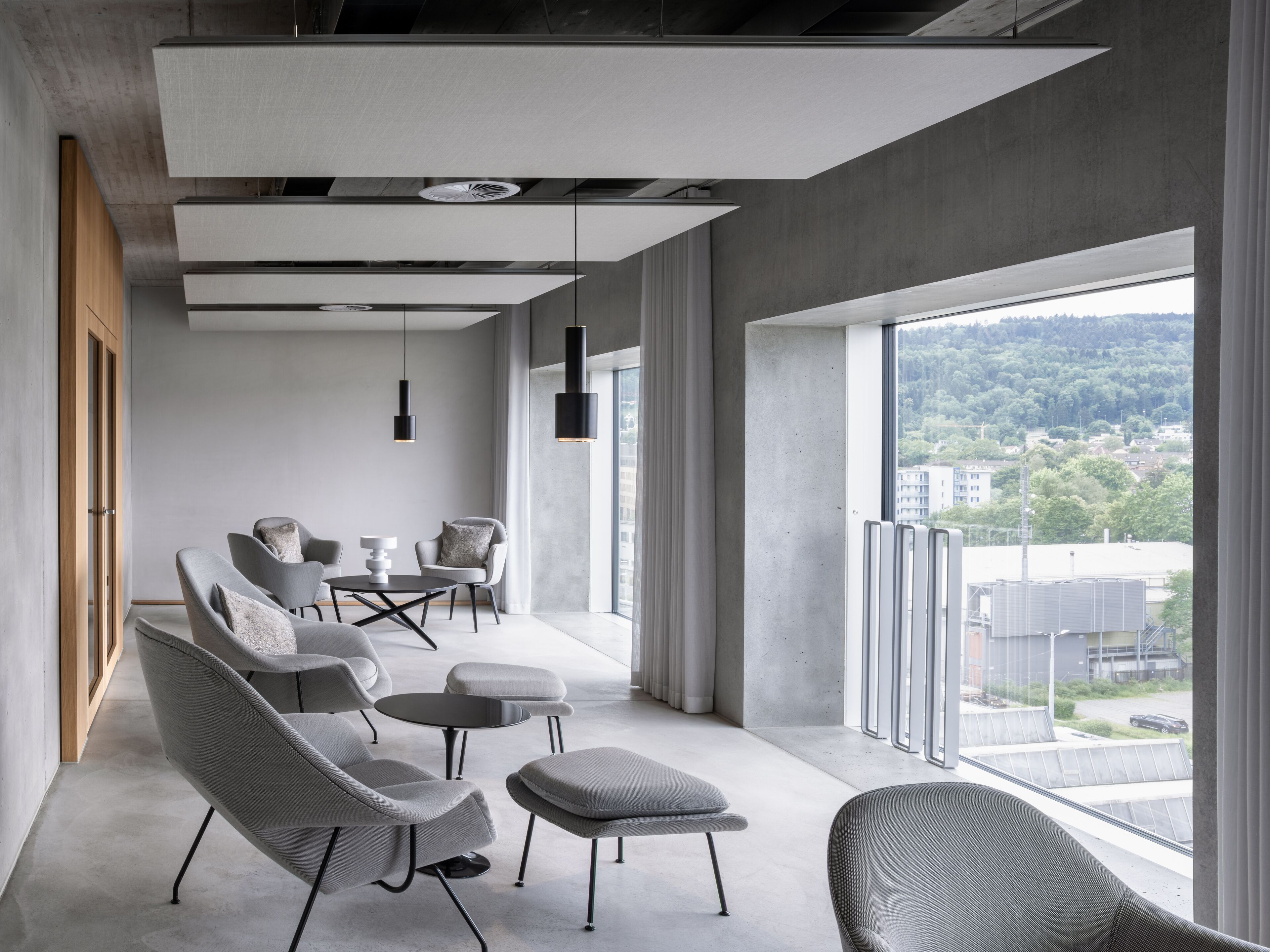 A modern interior with a seating area, large windows, and a view of a cityscape.