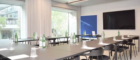 Ein moderner Konferenzraum mit langen Tischen, Stühlen und Gläsern.