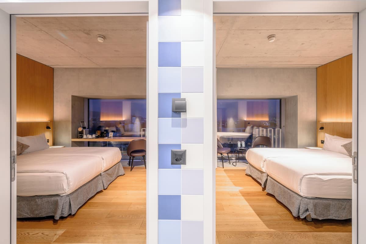 Une chambre d’hôtel avec deux lits, un bureau et une chaise.