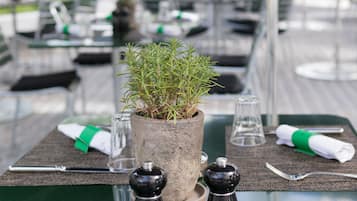 Une table à manger ornée d’une plante en pot, de salières et de poivrières, et recouverte d’une nappe verte.