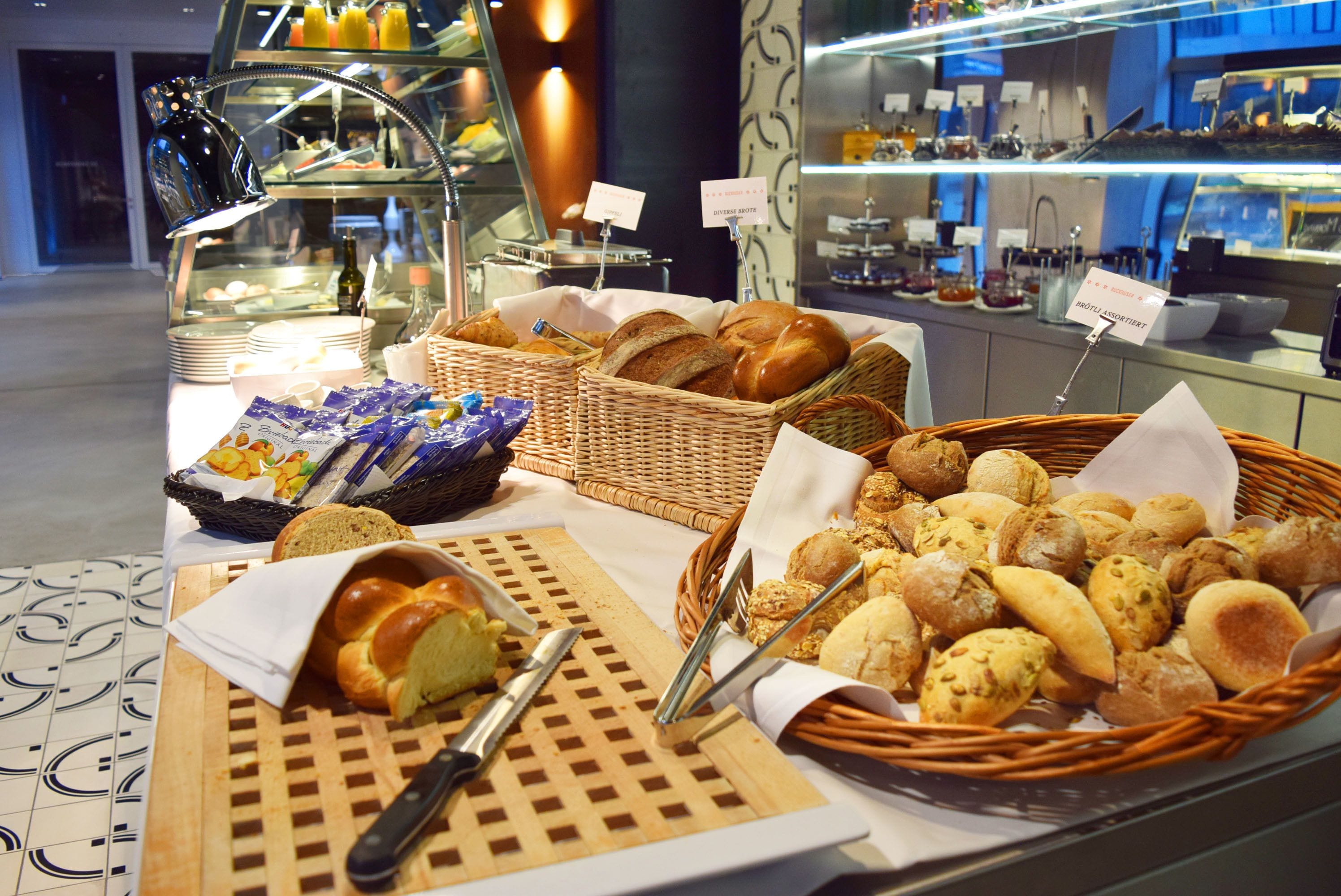 A buffet with various breads and pastries displayed in baskets and on a table.