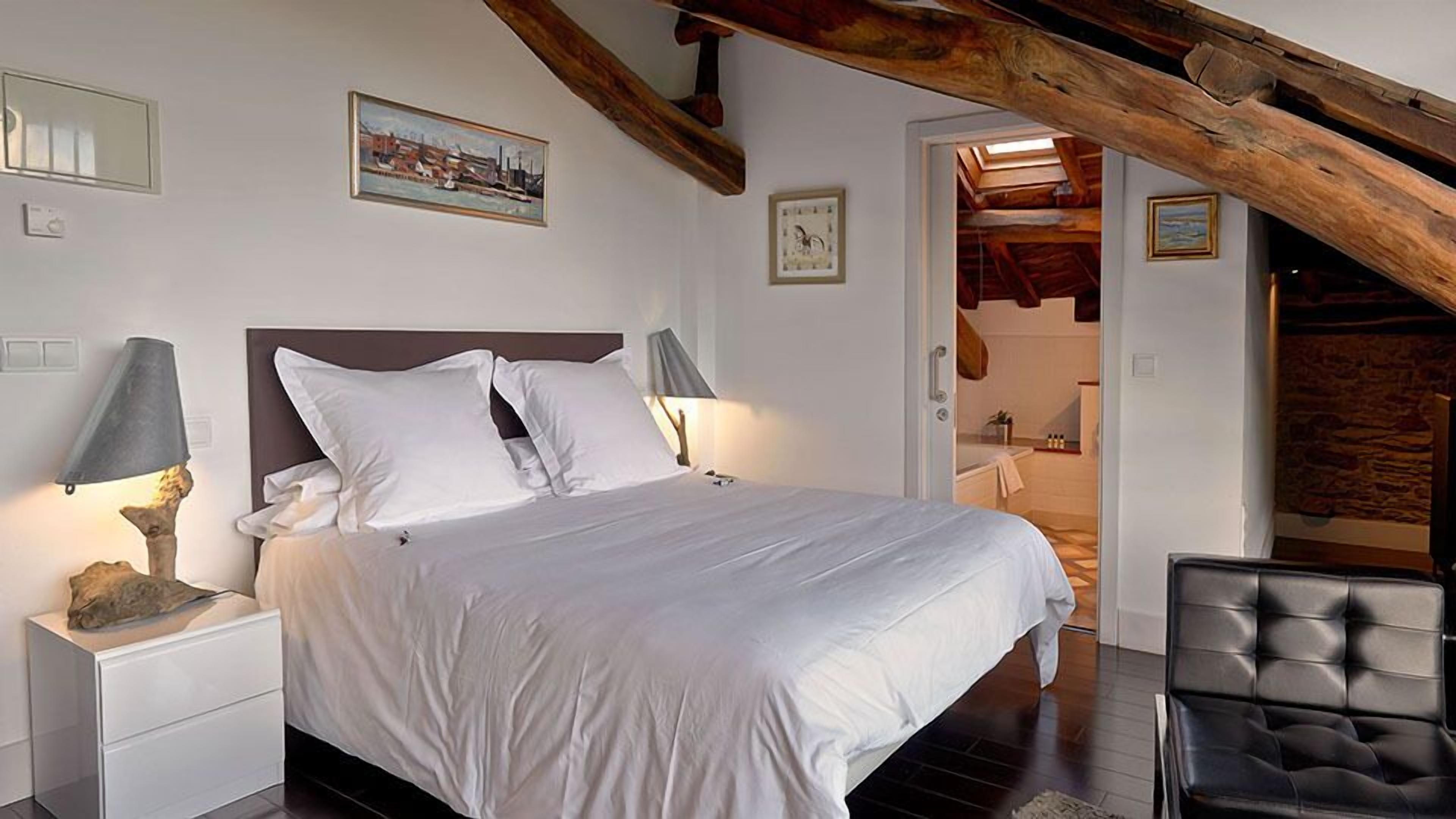 Une chambre à coucher avec un grand lit, deux lampes de chevet et une poutre en bois au plafond.