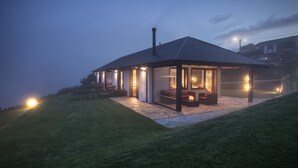 Una casa moderna con un porche cubierto, chimenea y un interior bien iluminado.
