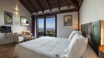 Un dormitorio con una cama grande, un escritorio, una silla y un televisor. Hay dos ventanas con vistas al exterior.