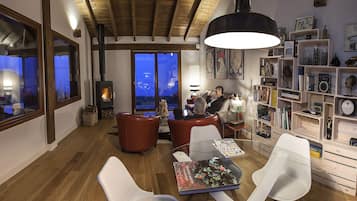 A cozy living room with a fireplace, comfortable seating, and a well-organized bookshelf.