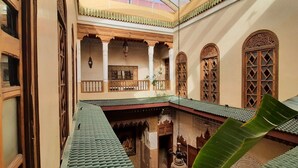 Une cour traditionnelle avec un toit en tuiles, des balcons en bois et des portes en bois richement décorées.