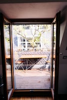 Puerta corrediza de vidrio que da a un patio exterior con una mesa y sillas de madera.