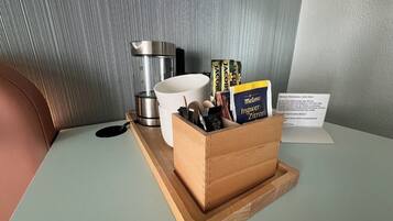 Ein kleiner Holztischchen mit einer Kaffeemaschine, einer weißen Tasse und einer Büchersammlung darauf.