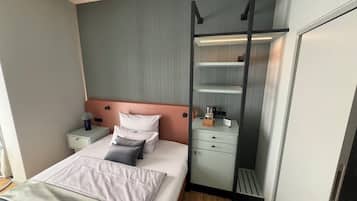 Una camera d'albergo moderna con un letto, comodini, un armadio e una parete attrezzata.
