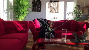 Una sala de estar con sofás rojos, una mesa de centro de madera y plantas verdes.