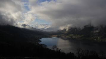 A panoramic view of a lake surrounded by mountains and clouds.