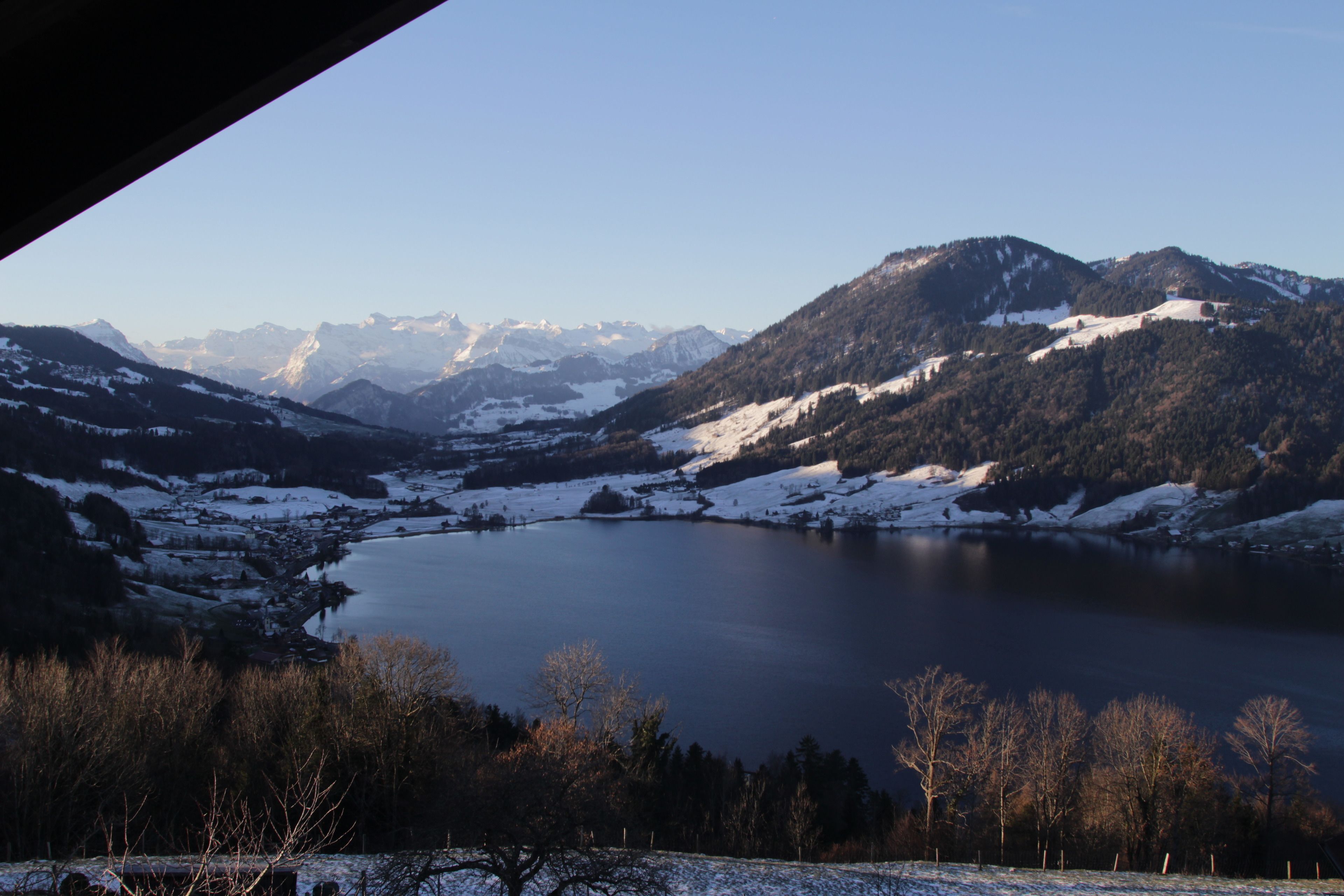 A mountainous landscape with a lake and snow-covered hills.