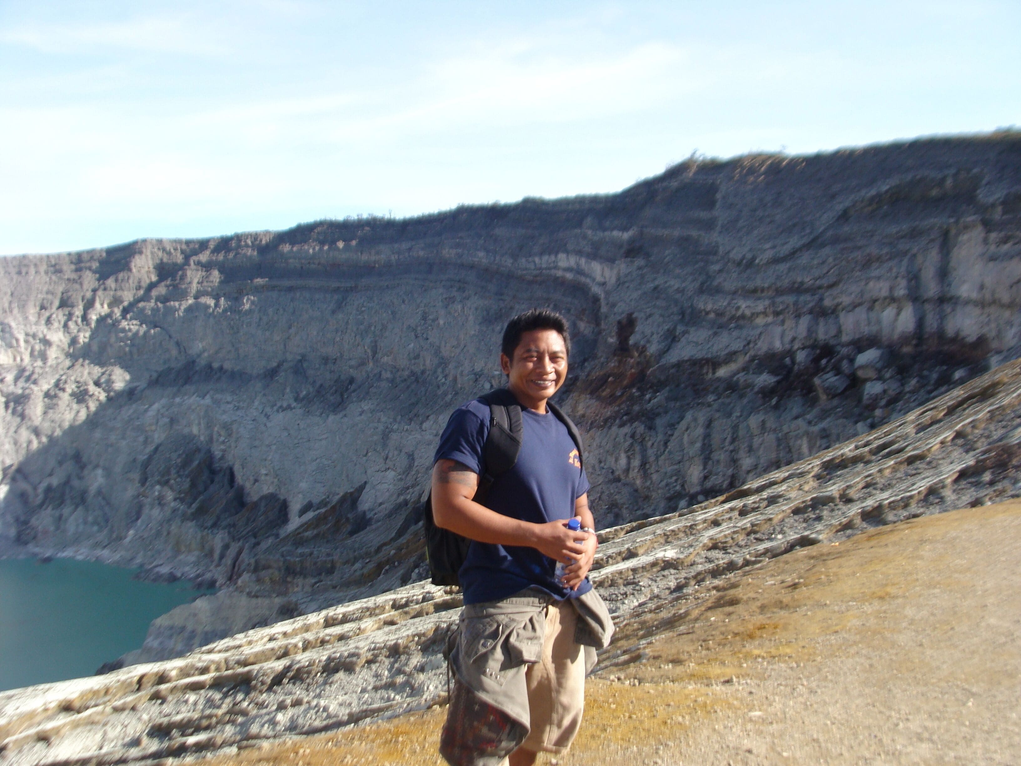 A person standing on a rocky terrain with a mountainous backdrop.