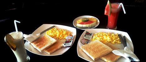 Two plates with toast, corn, and jam, a glass of milk, and a watermelon drink.