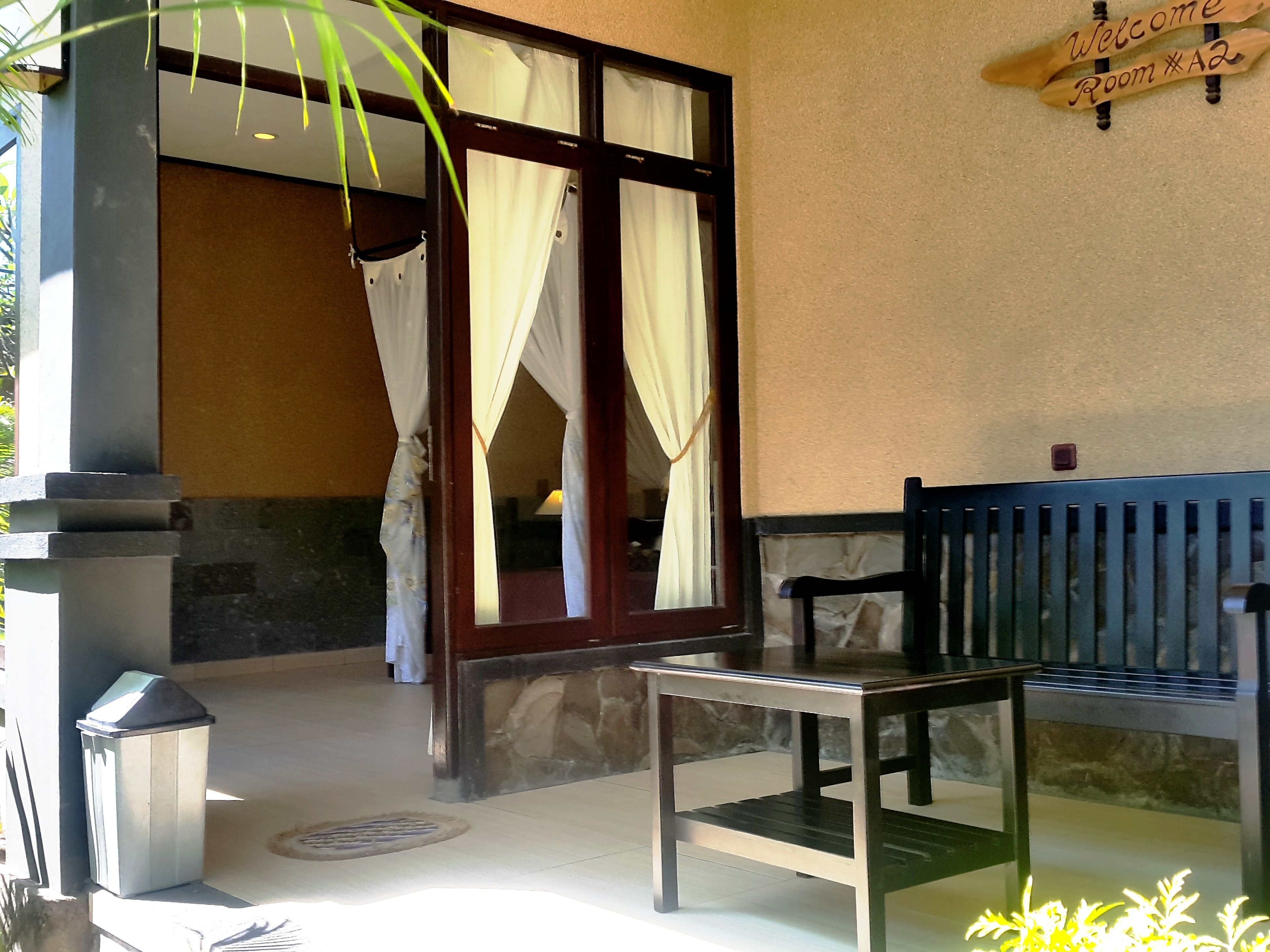 Una habitación con un banco de madera, un cubo de basura y un cartel de bienvenida.