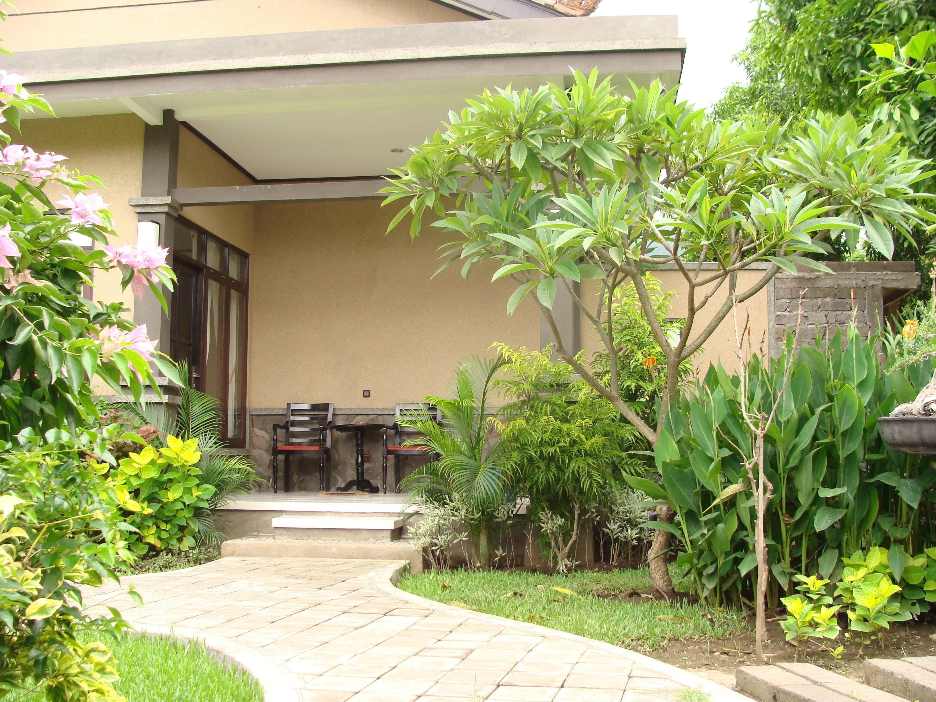 A garden pathway leading to a covered seating area with chairs and a table.