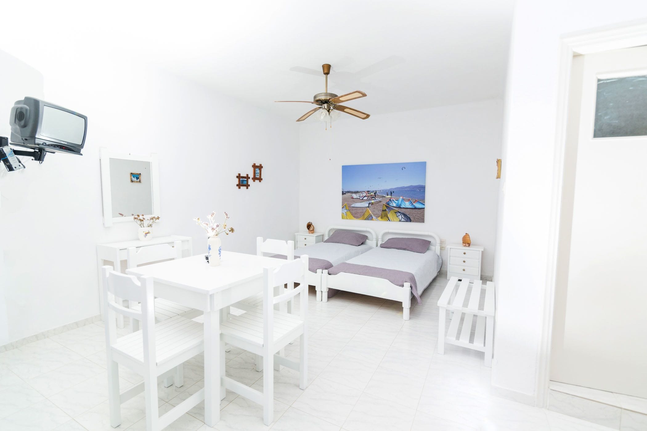 A bright, white room with a bed, a desk, and a chair.