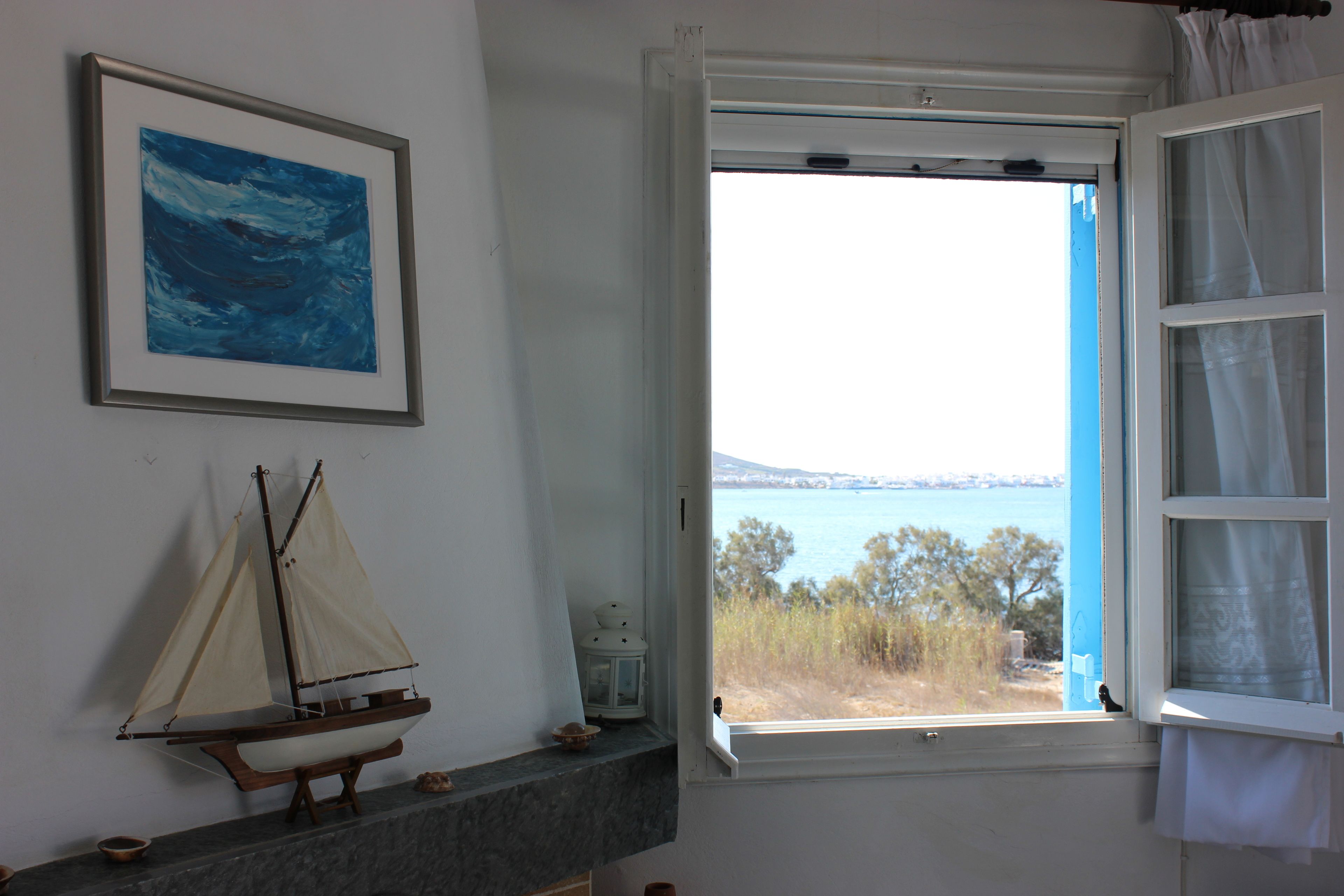 Una habitación con vista al mar, un cuadro enmarcado y un modelo de velero.
