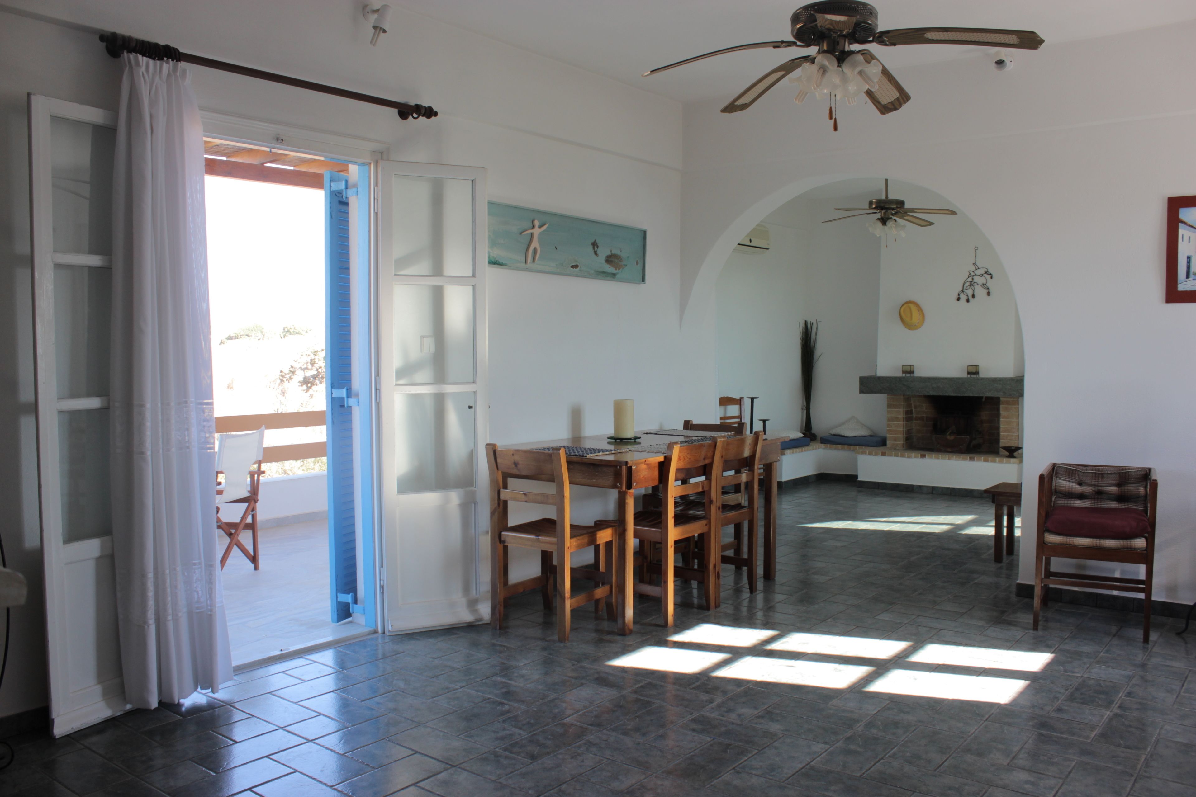A spacious living room with a dining area, a fireplace, and a ceiling fan.