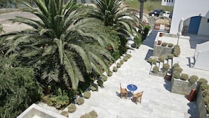 A rooftop terrace with palm trees, a seating area, and a view of the sea and boats.