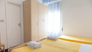 A room with two beds, a wardrobe, and a window with curtains. - Hotel Ronconi (Rimini)