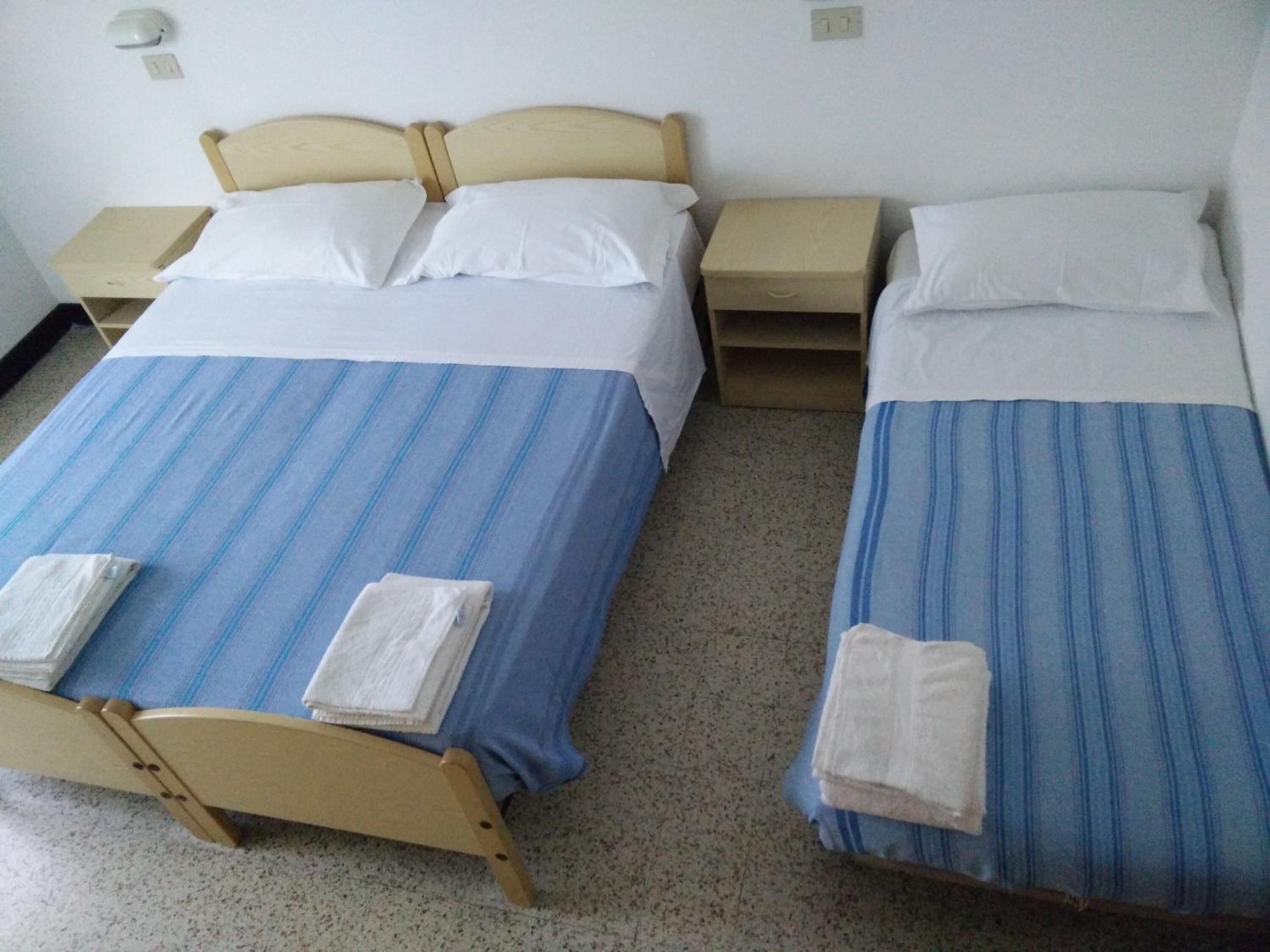 Two single beds with blue-striped bedding, white pillows, and matching nightstands.