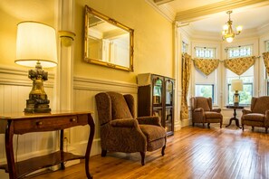 Classic design with a large mirror, table, lamp, and armchairs.