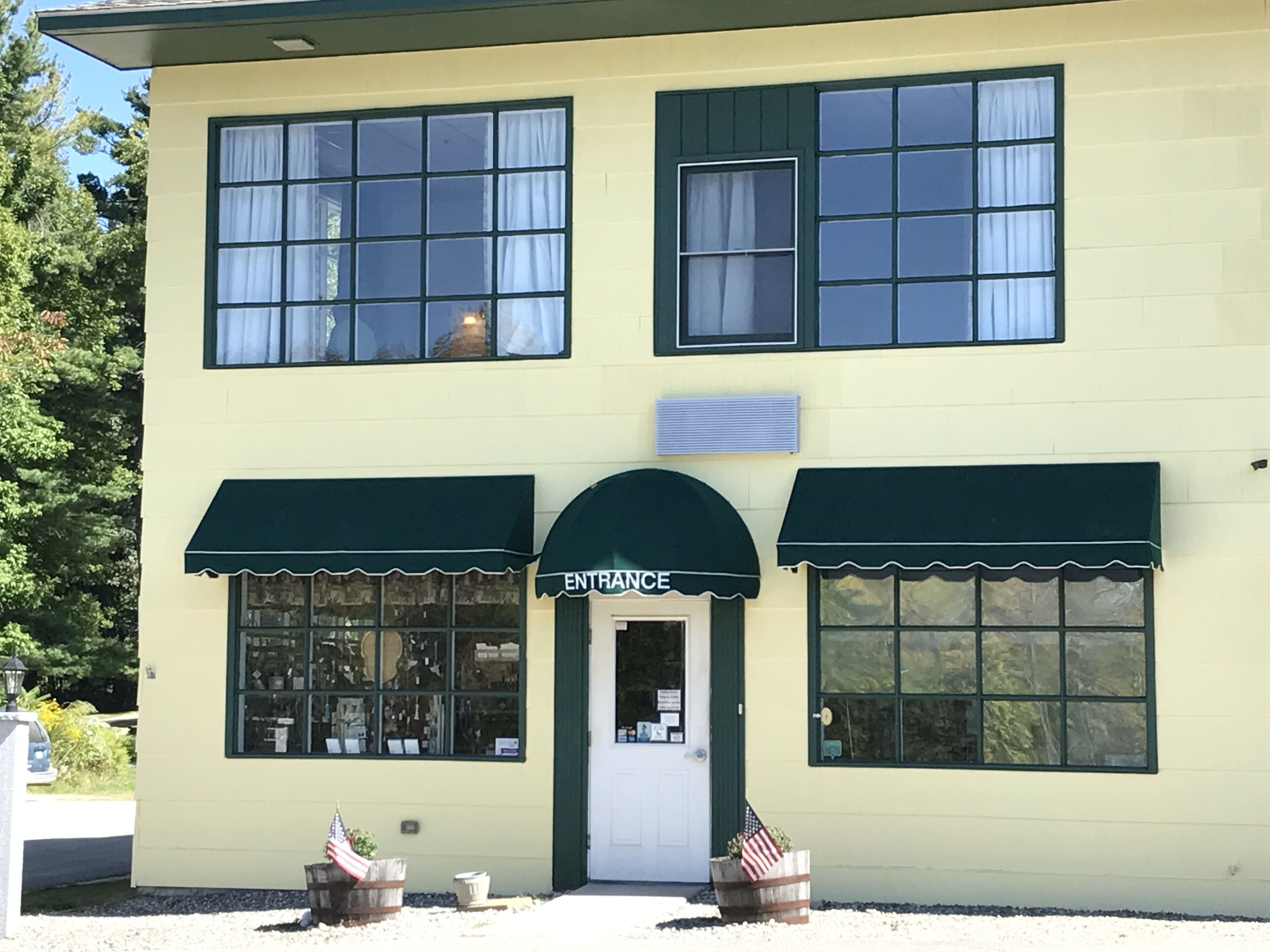 A two-story building with a green awning labeled "ENTRANCE" above the door.