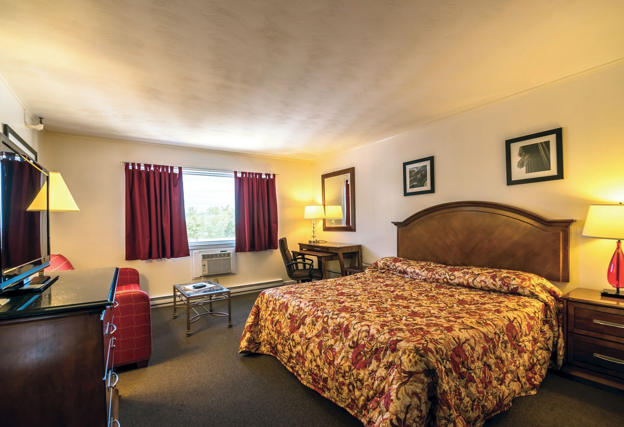 A hotel room with a bed, desk, chair, and a window with curtains.